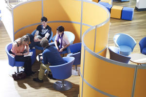 elevated view of students on blue seats in front of a yellow partition