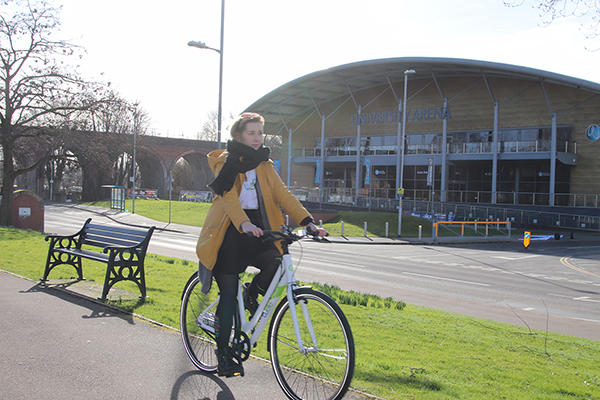 A woman is cycling on a Woo bike outside of the ӶƵ Arena on a winter day