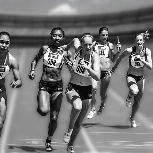 A group of female athletes are running on a racetrack