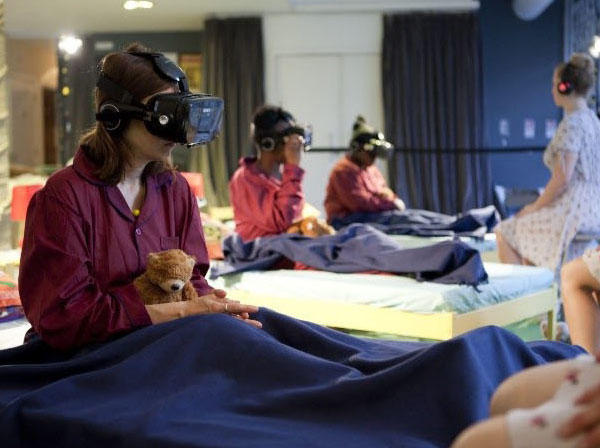 Several people are sitting up in beds wearing virtual reality helmets