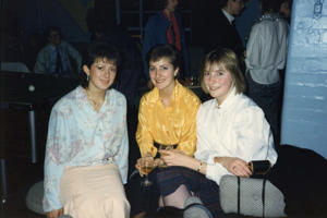 Three women sitting in a nightclub in 1980s clothing