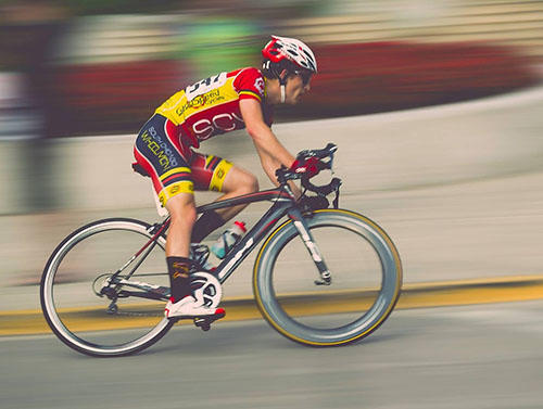 A brightly dressed competitive cyclist competes against a blurred background.