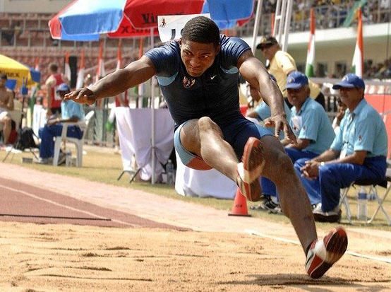A man is landing in a sand pit during a long jump competition