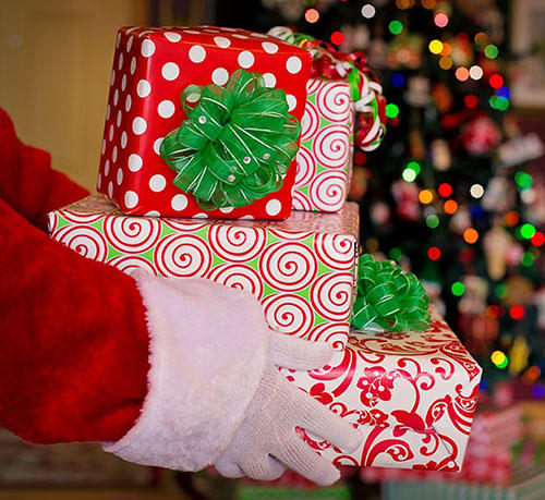 A close-up of Santa's hands holding a pile of wrapped presents
