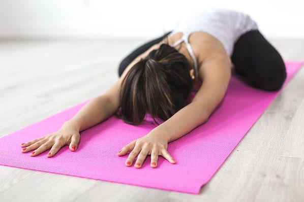 a lady is doing yoga on a pink mat