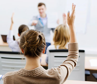 A girl is raising her hand in a classroom