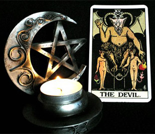 tarot card of the devil beside a star a moon and a candle